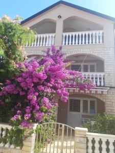 una casa con fiori viola di fronte di Apartment Petrčane a Petrcane