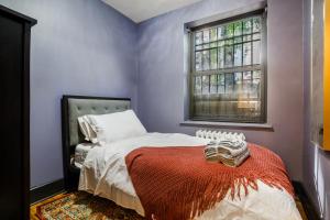 a bedroom with a bed with a red blanket and a window at Lamartine Chelsea in New York