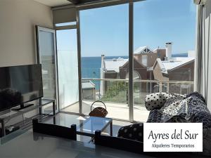 a living room with a tv and a large window at Ayres del Sur in Puerto Madryn
