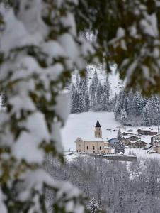 un pueblo cubierto de nieve con una iglesia y árboles en Casa Iride, en Canal San Bovo