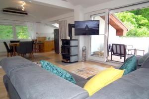 sala de estar con sofá y TV de pantalla plana en Baker's Pond Loft Apartment, en Velden am Wörthersee