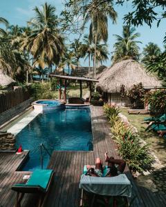 two people laying on chaise lounges next to a resort pool at Finca Escondida in Palomino