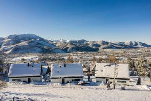 a house covered in snow with mountains in the background at udanypobyt OMG Houses in Kościelisko