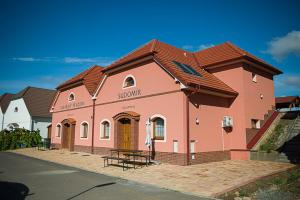 een groot roze gebouw met een bank ervoor bij Penzion Sudomír in Sudoměřice