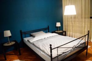 een slaapkamer met een bed met blauwe muren en 2 lampen bij Apartment J&M in Zagreb