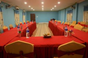 una sala conferenze con tavoli e sedie rosse e bottiglie d'acqua di Chitwan Forest Resort , Chitwan National Park a Sauraha Altre 37 foto