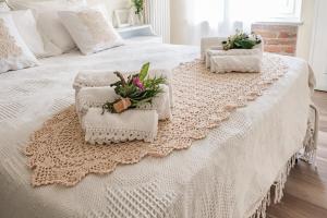 ein weißes Bett mit zwei Handtüchern und Blumen darauf in der Unterkunft Villa Curte Nicia in Nizza Monferrato