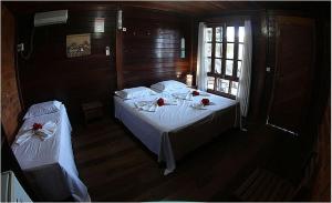 Un dormitorio con una cama con sábanas blancas y flores. en Pousada Capim Açu, en Fernando de Noronha