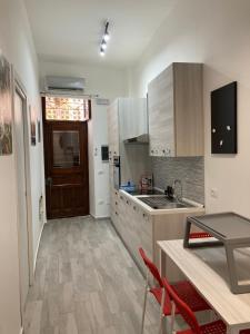 a kitchen with wooden cabinets and a table with red chairs at Rigoletto Holiday Home,Centrocittà Palermo in Palermo