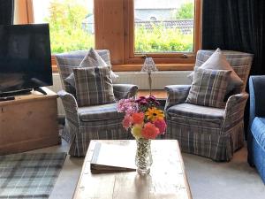 a living room with two chairs and a vase of flowers on a table at Aldersyde in Tighnabruaich