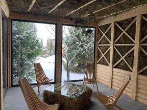 een afgeschermde veranda met een glazen tafel en stoelen bij SPA Hotel Zhyva Voda in Mizhhirya