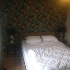 - un lit avec deux oreillers devant un mur fleuri dans l'établissement le gite de sandrine, à Réville