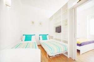a white room with two beds and a tv at Cuore di Sanremo apartment and free parking in Sanremo