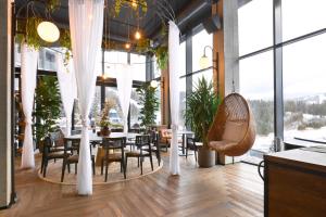 a restaurant with tables and chairs and large windows at Mountain Residence Apartments & Chalet in Bukovel