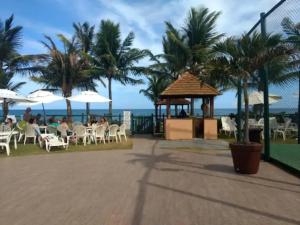 a restaurant on the beach with palm trees and the ocean at Flat Guarajuba Summer House - Bahia in Guarajuba