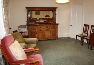 a living room with chairs and a dresser and a mirror at Guillemots in North Berwick