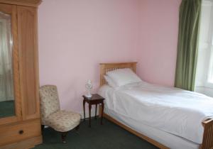 a bedroom with a bed and a chair and a window at Guillemots in North Berwick