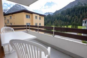 d'une table et de chaises blanches sur un balcon avec vue sur les montagnes. dans l'établissement Casa Irmella 12 - Arosa - alles komplett, à Arosa