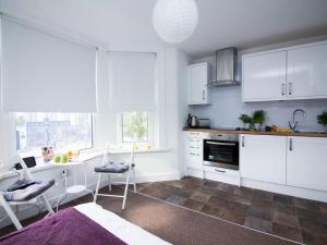イーストリーにあるBeddoe Apartments Premier Lodge Eastleigh near Winchester and Southamptonの白いキャビネット、テーブルと椅子付きのキッチンが備わります。
