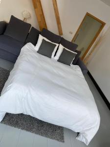 uma grande cama branca com almofadas e um sofá em À deux PATENIER de Dinant em Dinant