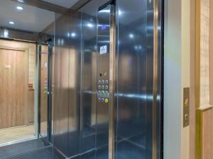 パリにあるBE YOU LUXURY APART'HÔTEL - LA POUDRÉEのガラスドア付きの客室内のエレベーター