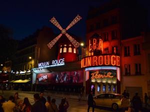 a building with a windmill in front of it at night at BE YOU LUXURY APART'HÔTEL - LA POUDRÉE in Paris