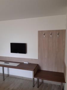 sala de estar con escritorio y TV en la pared en M47 Vendégház-Airport en Debrecen