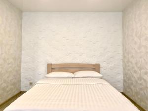 um quarto com uma cama com uma parede branca em ApartPoltava Світлі та затишні апартаменти в Скандинавському стилі ЦЕНТР БАНКІВСЬКИЙ ЧЕК em Poltava