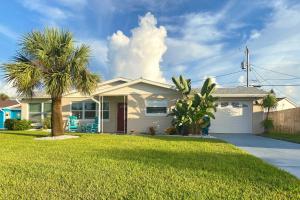 a white house with a palm tree in a yard at Bright Bungalow with Porch Walk to Ormond Beach! in Ormond Beach