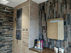 a bathroom with a shower with a tile wall at At Cedar Lodge Apartment in Ramsey