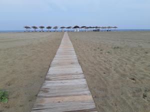 a wooden pathway on the beach with umbrellas at Lidra in Korinos