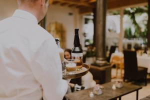 un uomo che tiene un vassoio con una bottiglia di vino di Vitalpina Hotel Schulerhof a Plaus