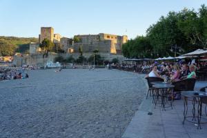 a group of people sitting at tables on a beach with a castle at Collioure Centre Ville, Calme, Clim in Collioure