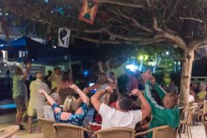 a group of people sitting in chairs with their hands in the air at Coconut Court Beach Hotel in Bridgetown