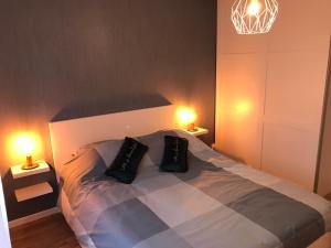 a bedroom with a bed with two pillows and two lights at F3 standing in Les Ulis