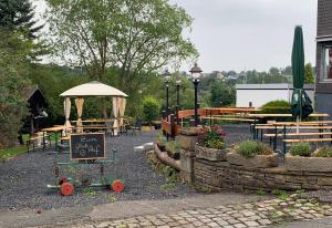 a garden with a sign and tables and benches at Ruhrpottpension Am Stöter in Witten