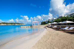 einen Strand mit Stühlen und einem Pavillon auf dem Wasser in der Unterkunft Hammock Cove Antigua - All Inclusive - Adults Only in Willikies