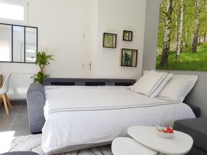 a bedroom with a large white bed and a table at Super Studio cosy proche de CDG - Jeux Olympique 2024 in Le Thillay