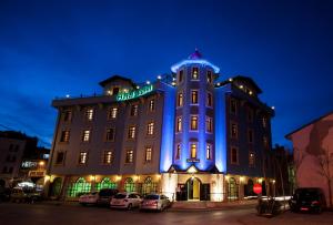 un edificio iluminado de azul con coches aparcados delante en Rumi Hotel en Konya
