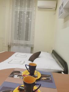 una mesa con dos tazas encima de una cama en Baross-hat 4 en Szolnok