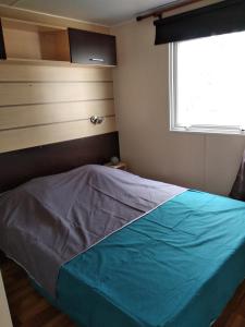 a bedroom with a bed with a blue blanket at Camping Parc des 7 Fonts in Agde