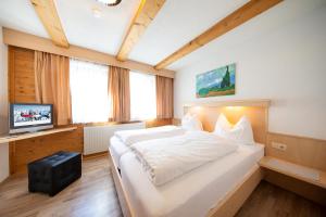 a bedroom with a large white bed and a television at Haus Veronika in Sölden