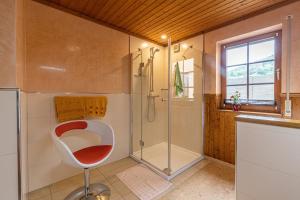 a bathroom with a shower and a red chair in it at Ferienwohnung-Mediterran in Einruhr +22 photos