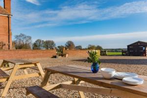 a wooden picnic table with plates and a vase of flowers on it at Cavallo Barn by Bloom Stays in Canterbury