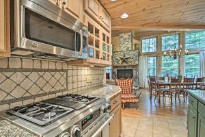 a kitchen with a stove and a dining room at Rustic and Modern Home with Fire Pit on Tower Pond! in Onaway +24 photos