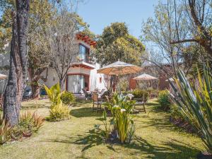 un jardin avec des chaises et des parasols en face d'une maison dans l'établissement Hotel Casa de Familia de San Cristobal, à San Cristóbal de Las Casas