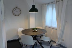 uma mesa de jantar com cadeiras brancas e um relógio em INSIDEHOME Apartments - Ático de Calle Mayor em Palencia