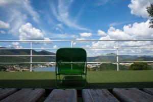 een groene stoel zittend op een bank kijkend naar een uitzicht bij Amsterdam lofts 2 in Poços de Caldas