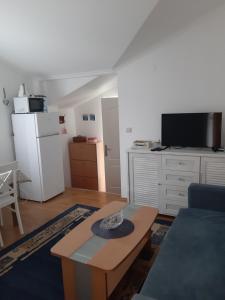 a living room with a table and a white refrigerator at Apartmani Stipanic Tivat in Tivat