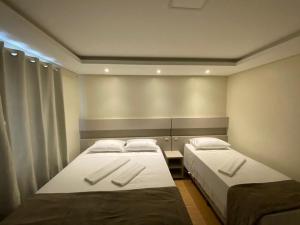 a bedroom with two beds with white pillows at Hotel Joaçaba in Joaçaba